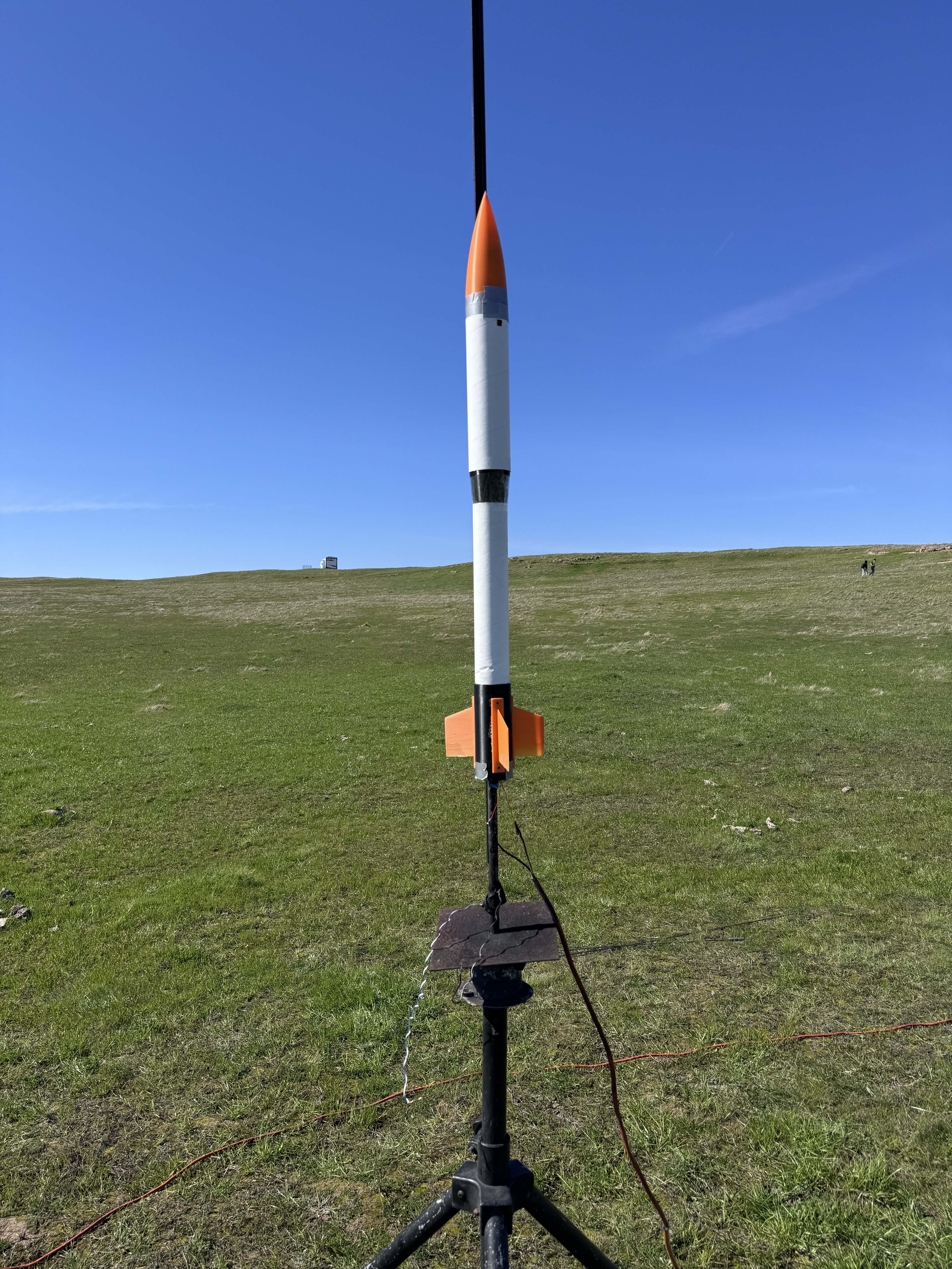 White and orange model rocket on launch stand